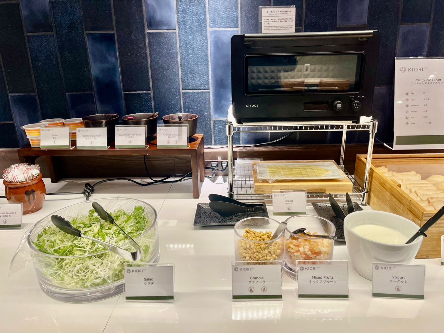 A buffet area with various food options including salad, granola, mixed fruits, yogurt, and cheese.