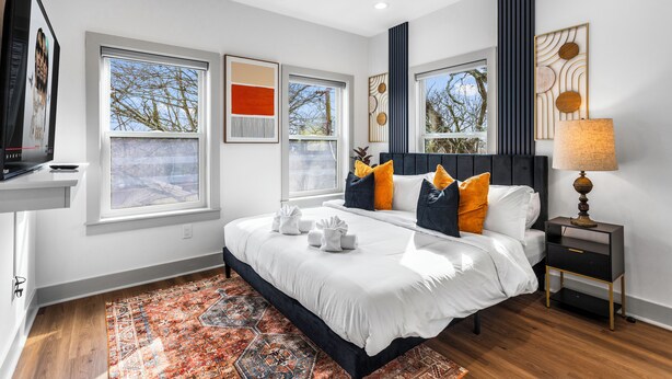 Un dormitorio moderno con una cama grande, un ventilador de techo y vistas al exterior a través de las ventanas.
