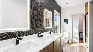 Un baño moderno con dos lavamanos, un espejo grande y un papel tapiz estampado.