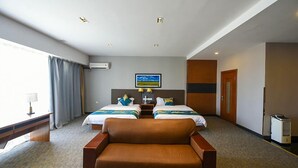 Habitación de hotel con dos camas, un sofá, un escritorio y un televisor.