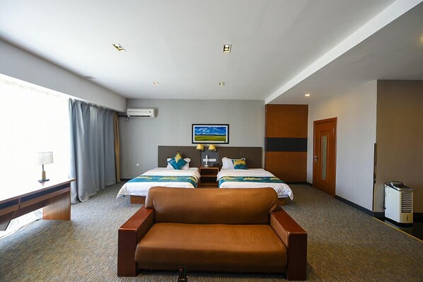 Ein Hotelzimmer mit zwei Betten, einem Schlafsofa, einem Schreibtisch und einem Fernseher.