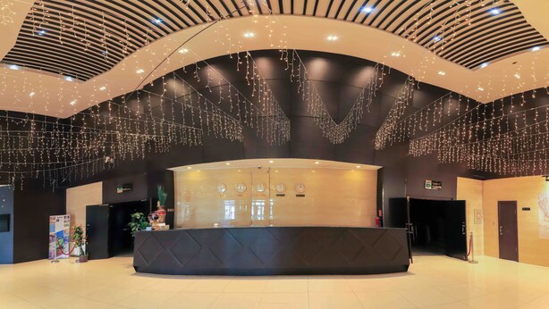 Un área de recepción moderna con un mostrador curvo, varios relojes y luces colgantes.