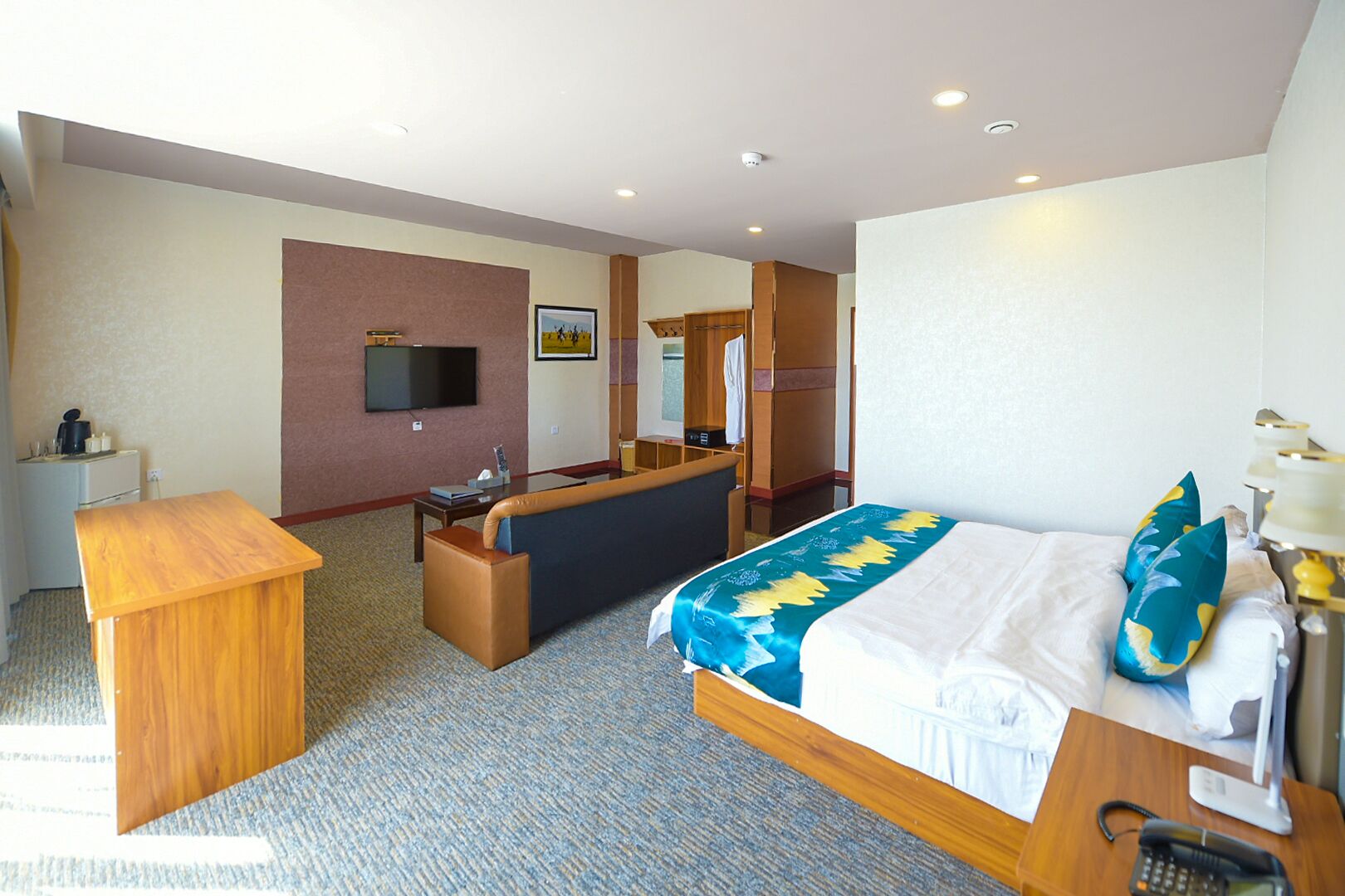 Una habitación de hotel con cama, escritorio, sofá, televisor y espejo.