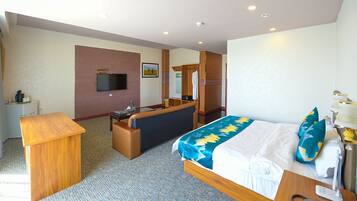 Una habitación de hotel con cama, escritorio, sofá, televisor y espejo.