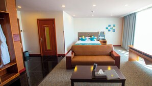 Habitación de hotel con cama, sofá, escritorio y armario.