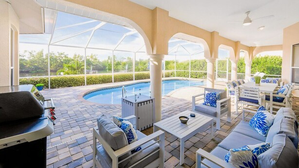 A covered outdoor area with a pool, seating, and a grill. - Villa Blu- SW Cape Coral- Sleeps 10- Gulf Access Heated Pool Home (Cape Coral)