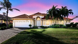 A two-story house with a tiled roof, a garage, and a well-maintained lawn. - Villa Blu- SW Cape Coral- Sleeps 10- Gulf Access Heated Pool Home (Cape Coral)