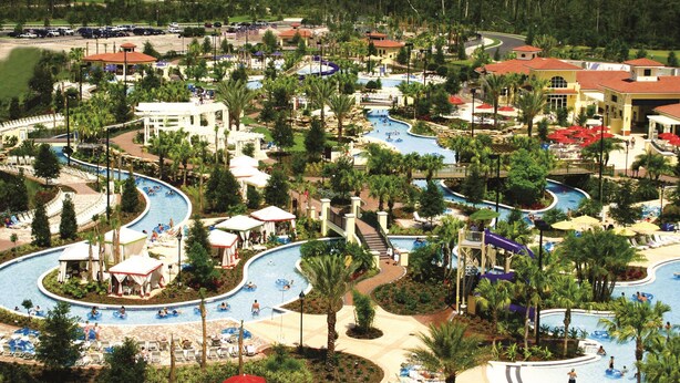 A resort with multiple swimming pools, palm trees, and a large building with a red roof.