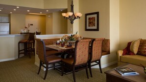 A dining area with a table, chairs, and a chandelier. There is a sofa and a coffee table in the living area.