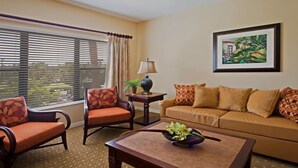 A living room with a sofa, two armchairs, a coffee table, a lamp, and a framed picture on the wall.