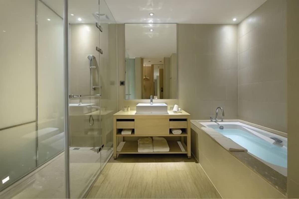 A modern bathroom with a glass shower enclosure, a sink with a vanity, and a standalone bathtub.