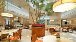 A spacious hotel lobby with multiple dining areas, a central planter with flowers, and a high ceiling with natural light. - Century Hotel (Taitung)