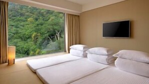 A hotel room with two beds, a TV, and a window with a view of greenery. - Century Hotel (Taitung)
