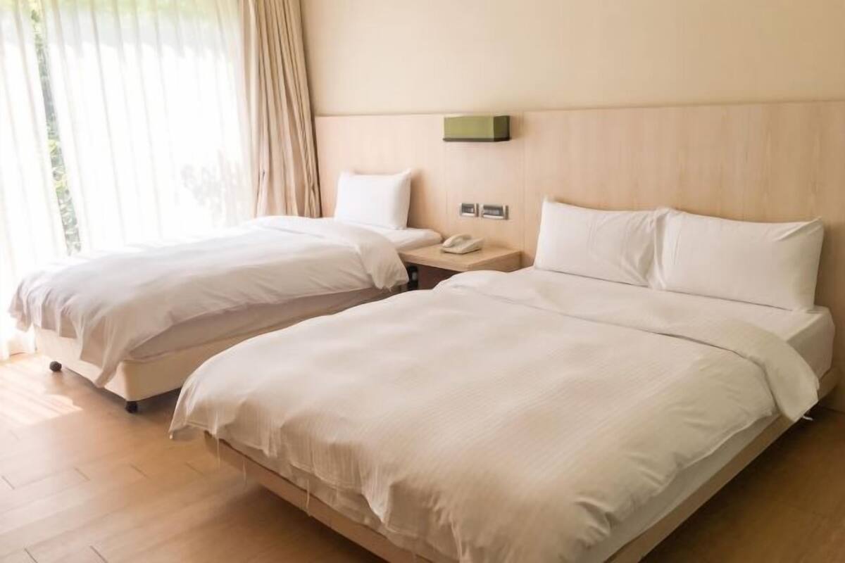 Une chambre d’hôtel avec deux lits, une table de chevet avec un téléphone et un luminaire fixé au mur.