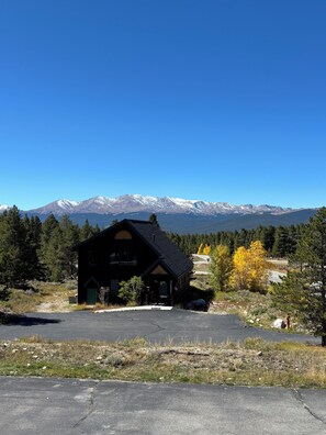 A lodge with a dark exterior, a front porch, and a view of snow-capped mountains in the background. - Wonderful 2-bedroom townhome in Leadville - 30+ night rental (Leadville)