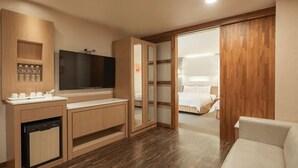Habitación de hotel con un armario de madera, un televisor de pantalla plana, un sofá y una puerta corredera que da a la cama.