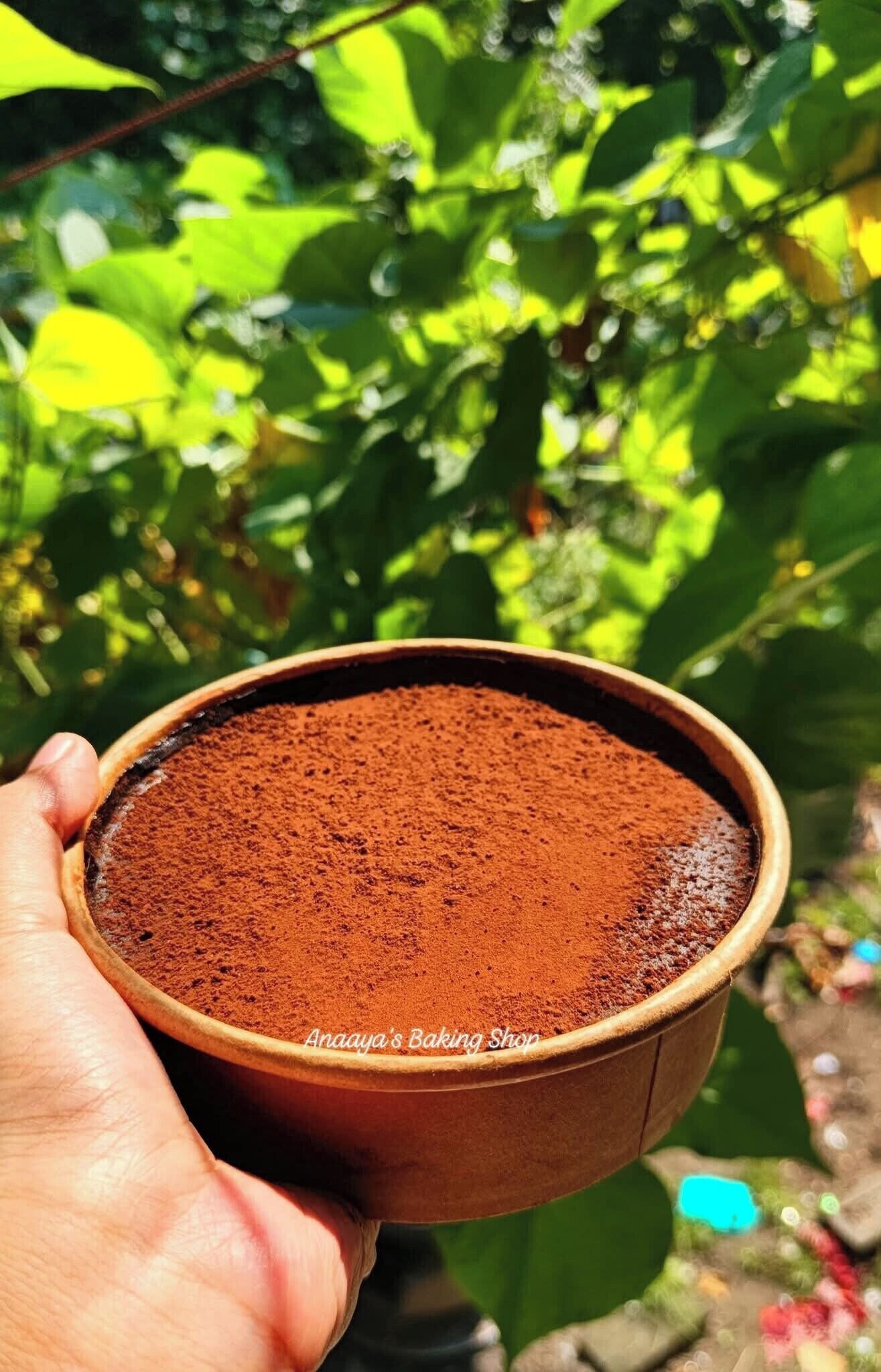 A hand holding a bowl of cocoa powder.