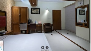Una camera d'albergo con un letto, un armadio, una scrivania, una sedia e uno specchio grande.