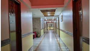 Un corridoio con porte su entrambi i lati, un lampadario rosso al soffitto e un pavimento piastrellato.