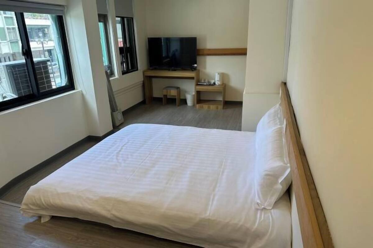 Ein Hotelzimmer mit Bett, Fernseher, Schreibtisch und Fenster.
