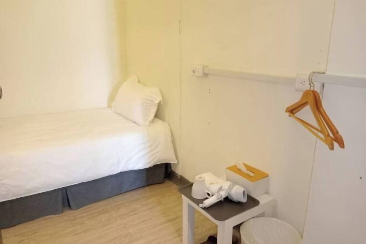 Ein Hotelzimmer mit einem Bett, einem kleinen Tisch mit Pflegeprodukten und einem Handtuchhalter.