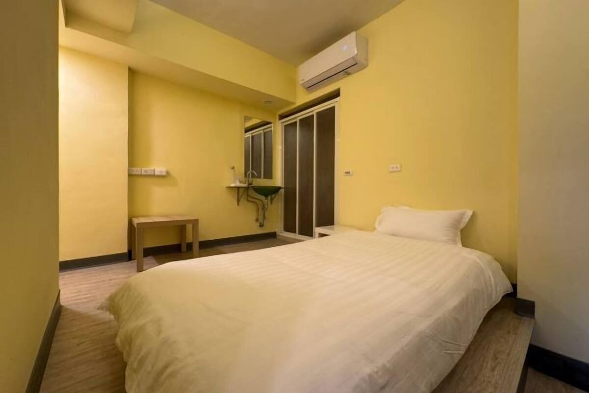 Ein Hotelzimmer mit einem Bett, einem kleinen Tisch, einem Spiegel und einer Klimaanlage.