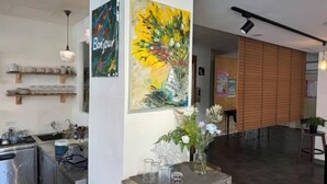 A modern kitchen with stainless steel appliances, a wooden shelf with kitchenware, and a vase with flowers on a table. - Bantshiann Hualie Hotel (Hualien)