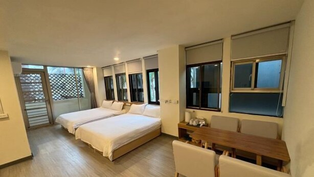 A bedroom with two beds, a wooden table, and a chair. - Bantshiann Hualie Hotel (Hualien)