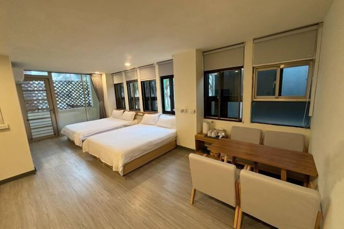 Ein Schlafzimmer mit zwei Betten, einem Holztisch und einem Stuhl.