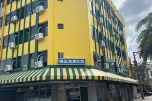 A multi-story building with a yellow facade and green accents, featuring air conditioning units and a sign indicating a hotel. - Bantshiann Hualie Hotel (Hualien)