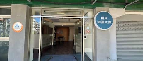 A hotel entrance with a glass door, a ramp leading inside, and a sign indicating the hotel's name.