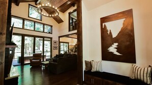 A spacious interior with a large window, a wooden ceiling, and a seating area with a bench and cushions. - Grays Crossing Luxury Cabin w/ Spa & Putting Green (Truckee)