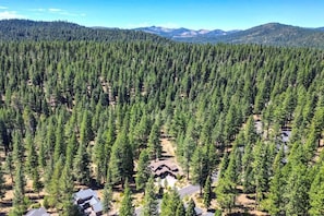 A forested area with a cluster of cabins and a mountain range in the background. - Basecamp Luxury Truckee retreat in Grays Crossing (Truckee)