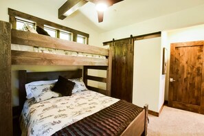 A bunk bed with a wooden headboard and a lower bed with a patterned bedspread. - Grays Crossing Luxury Cabin w/ Spa & Putting Green (Truckee)