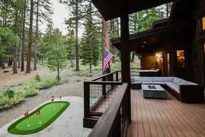 Une terrasse en bois avec un espace salon et un mât portant le drapeau américain.