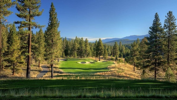 A golf course with a clear path, surrounded by tall pine trees and distant mountains. - Basecamp Luxury Truckee retreat in Grays Crossing (Truckee)