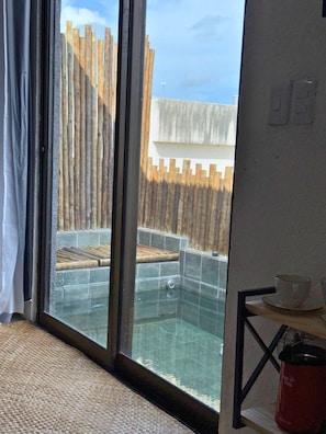 Ein Zimmer mit Glastür, die zu einem Poolbereich führt, mit Holzzaun und Fliesenwand.