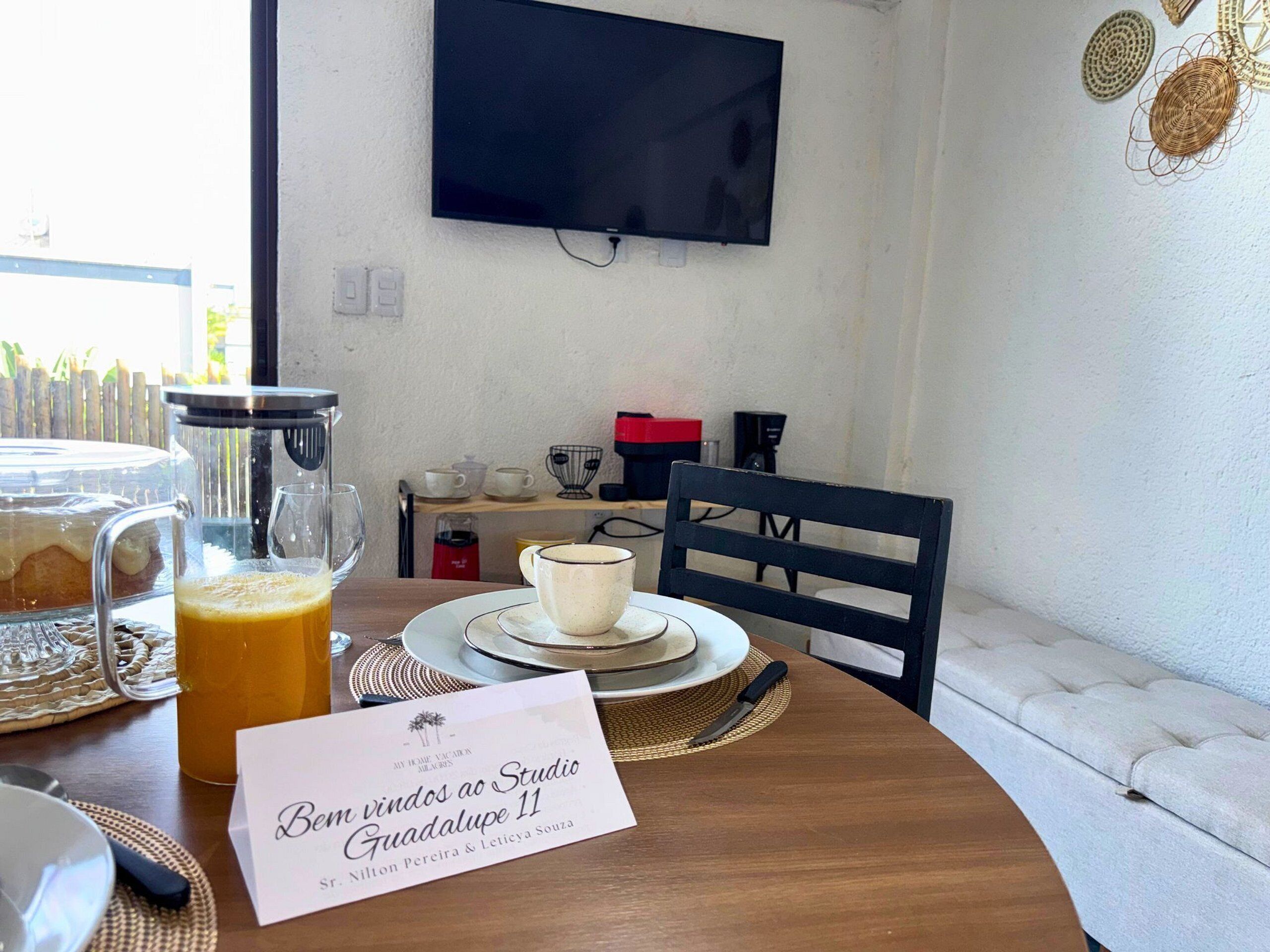 Una mesa con una cafetera, un jarro de vidrio y una taza.