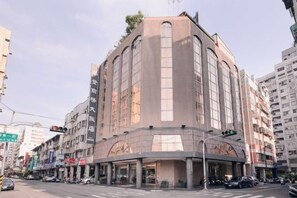 A multi-story hotel with a curved facade, large windows, and a ground-level entrance. - Waughden Business Hotel (Taichung)