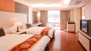Habitación de hotel con dos camas, televisión, escritorio y vistas al exterior.