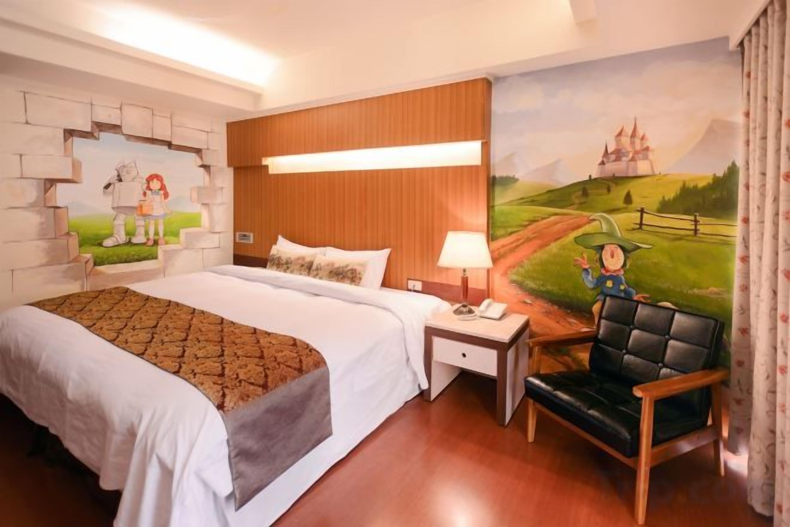 Una habitación de hotel con una cama grande, una mesita de noche, una silla y un mural en la pared.