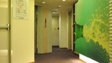A hallway with a green wall mural, a door with a map, and a carpeted floor.