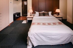 A hotel room with a large bed, two bedside tables, a desk, and a wardrobe. - Waughden Business Hotel (Taichung)