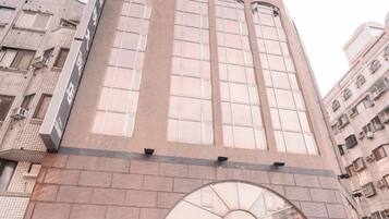 Un immeuble à plusieurs étages, doté d’une entrée arquée imposante et de grandes fenêtres.