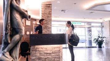 A reception area with a receptionist, a guest, and a statue.