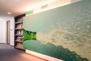 A hallway with a large wall map, a bookshelf, and a door. - Waughden Business Hotel (Taichung)