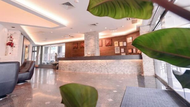 Un moderno vestíbulo de hotel con mostrador de recepción, zona de estar y amplias ventanas.