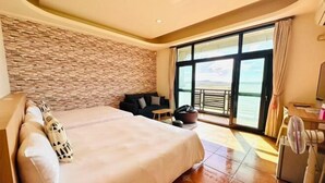 Quarto de hotel com uma cama grande, parede de pedra, varanda e vista, além de um ventilador.