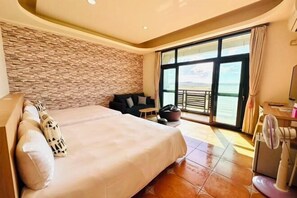 A hotel room with a large bed, a stone wall, a balcony with a view, and a fan. - Sun Shine Bed and Breakfast (Pingtung)