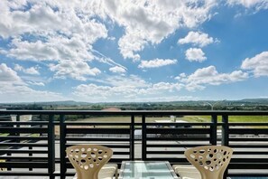 A balcony with two chairs and a table, overlooking a runway and distant landscape. - Sun Shine Bed and Breakfast (Pingtung)